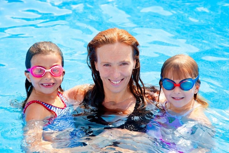 Woman and children smiling in a swimming pool
